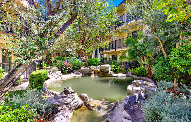 a pond in a garden with trees and rocks at Willow Tree Apartments, Torrance