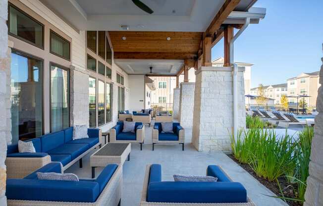 a patio with blue couches and chairs and a pool in the background at 55 Fifty at Northwest Crossing, Texas, 77092
