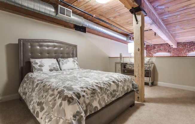 View of Bedroom, Showing Furnishings and Loft-Style Layout, Wooden Beam, View of Brick Wall at Alpha Mill Apartments