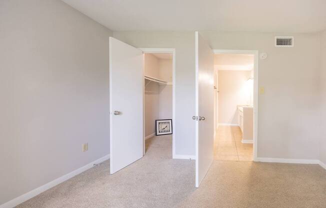 A room with a white door and a carpeted floor.
