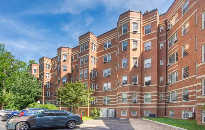 a large red brick apartment building with cars parked outside