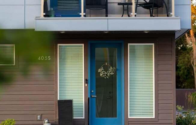 A modern house with a blue door and a balcony with flowers.
