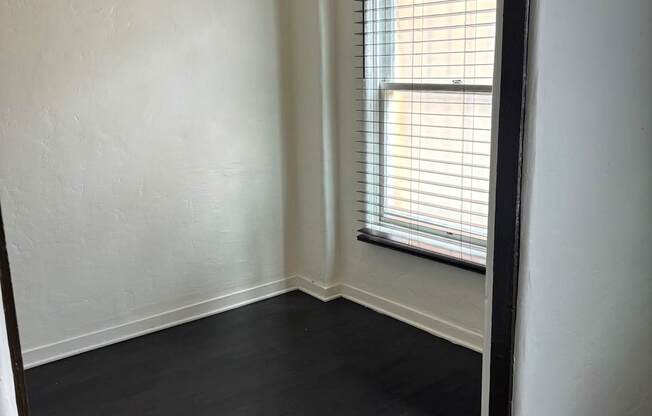 an empty room with wood floors and a window