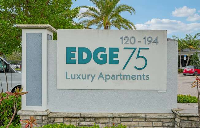 a sign for edge 75 luxury apartments in front of a palm tree