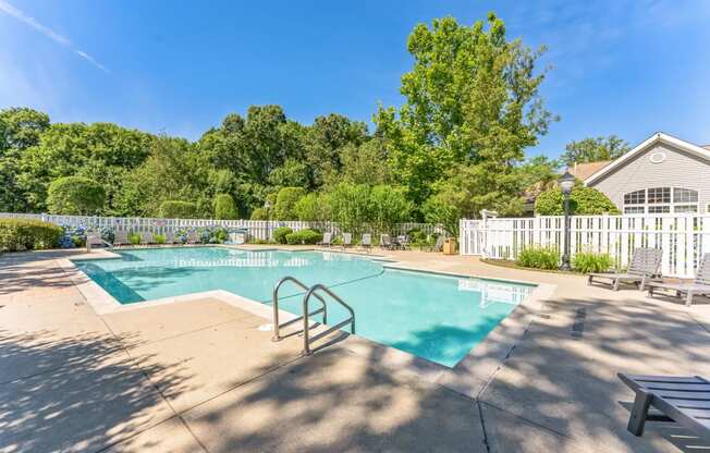 a swimming pool with a fence and a house in the background