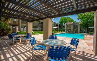 A patio with blue chairs and a table under a roof.