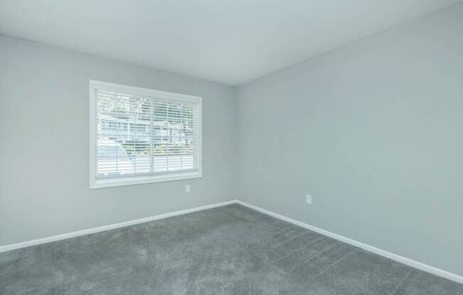 A room with a window and a grey floor.