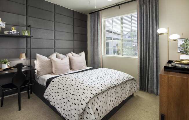 a bedroom with a bed and a desk and a window