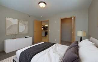 a bedroom with a bed and a door to a bathroom. Fargo, ND Urban Plains Apartments