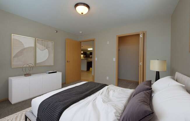 a bedroom with a bed and a door to a bathroom. Fargo, ND Urban Plains Apartments
