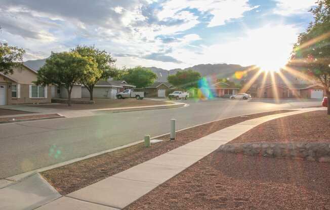 a street with houses and trees and the sunset  at Village of Cottonwood Springs in El Paso, TX 