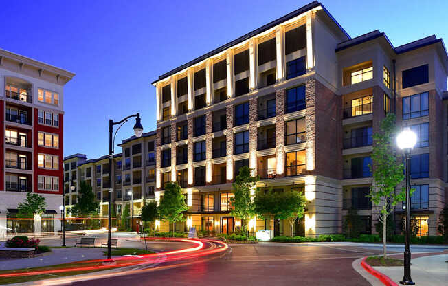 A modern apartment building with a lit walkway in front.