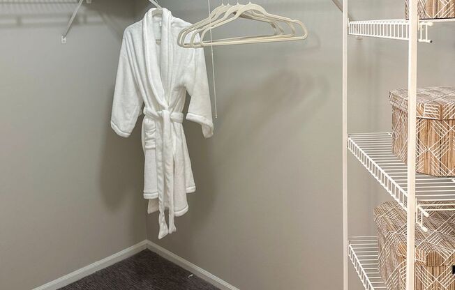 a walk in closet with a white robe hanging on the wall