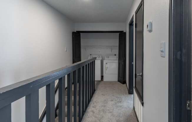 a hallway with a railing and a kitchen in the distance