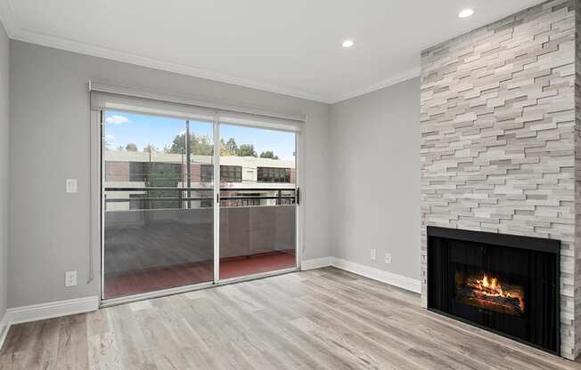 Cozy stone-walled fireplace in the living room with view of balcony.