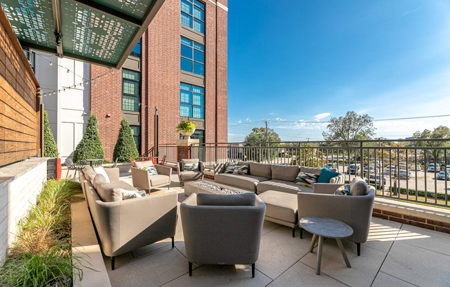 A patio with grey couches and a table with a glass roof.