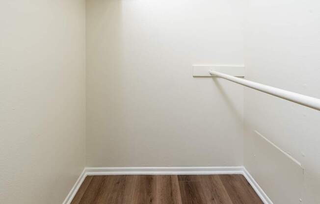 A white wall with a wooden floor and a white rail.