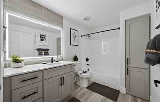 an all white bathroom with gray cabinets and a black shower curtain