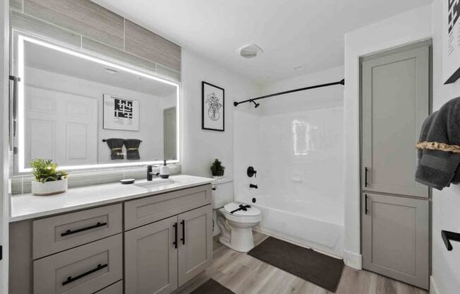 an all white bathroom with gray cabinets and a black shower curtain