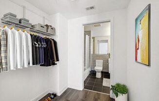 a closet with clothes and a bathroom with a toilet
