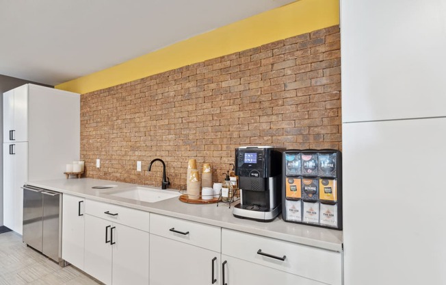 a kitchen with white cabinets and a brick wall