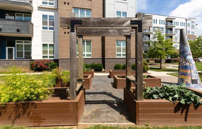 a courtyard with wood planters and a sculpture in front of an apartment building  at Abberly Noda Vista Apartment Homes, Charlotte, North Carolina