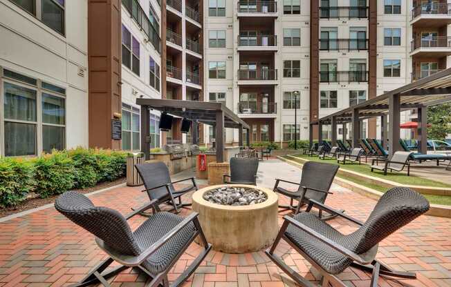A patio with chairs and a fire pit in front of a building.
