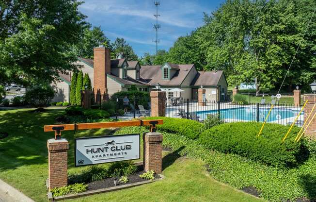 a home with a sign for hunt club in front of a swimming pool