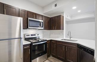 a kitchen with dark wood cabinets and stainless steel appliances at The Legends at Eagle Mountain Lake, Fort Worth, Texas