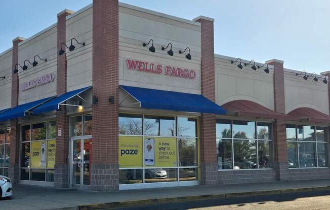 A Wells Fargo bank with a blue awning and a white car parked in front.