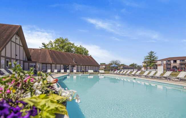 a large swimming pool with white lounge chairs and a building with trees