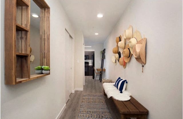 Hallway with plank flooring, mirror,  and storage bench with hats haning on the wall for artsy decoration at Arabella Apartment Homes, Washington, 98155