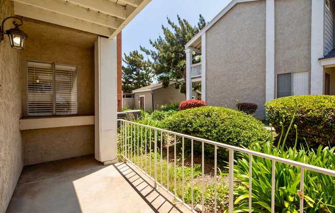 A patio with a white railing and a wall with a window.