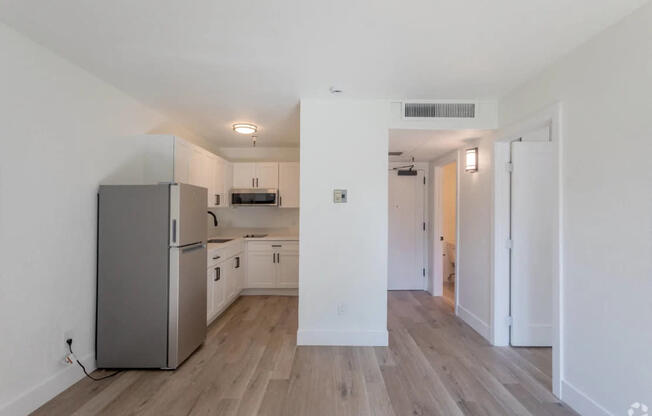 A kitchen with a refrigerator, microwave, and oven.