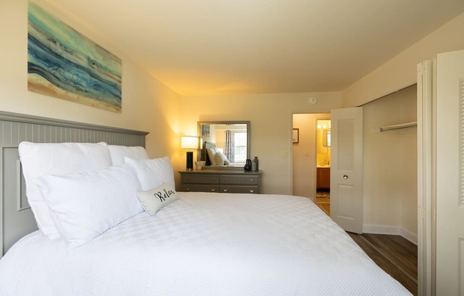 Guest bedroom with bed and dresser and double door closet at Woodridge Apartments.