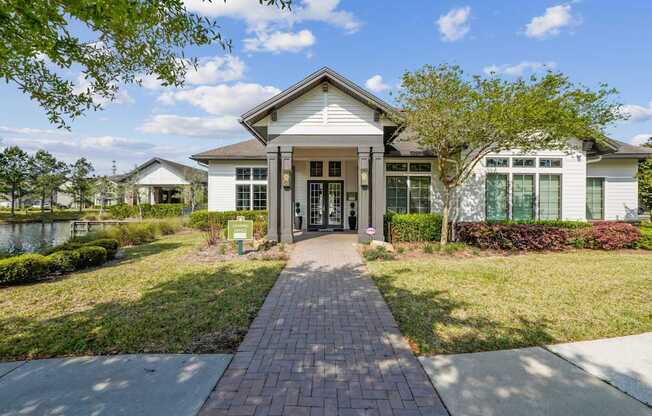 A white building with a brick pathway leading to the front door.