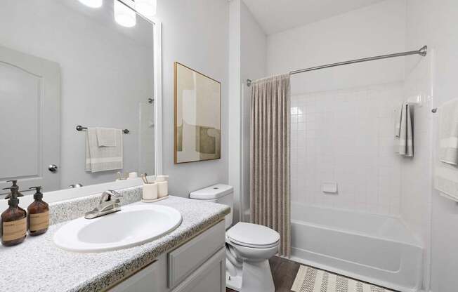 A white bathroom with a sink, toilet, and shower.