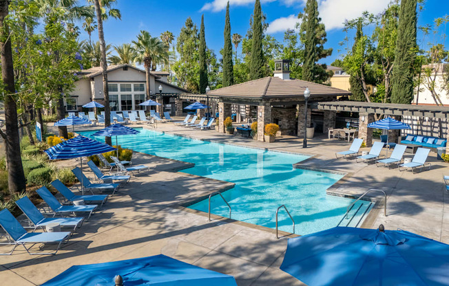 A large swimming pool surrounded by blue lounge chairs and umbrellas.