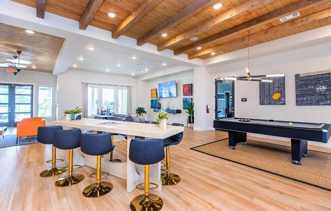 A room with a pool table and bar stools.