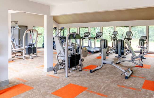 A gym with orange mats and a variety of exercise equipment.