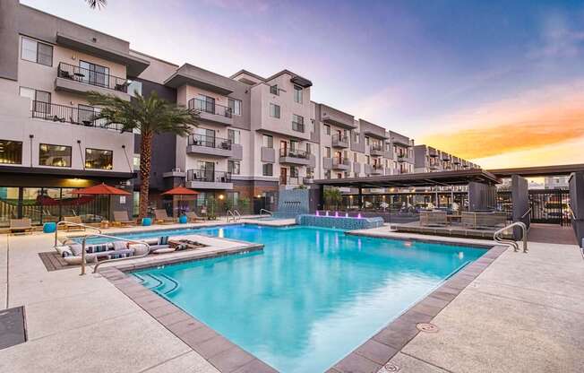 A large swimming pool is surrounded by apartment buildings.