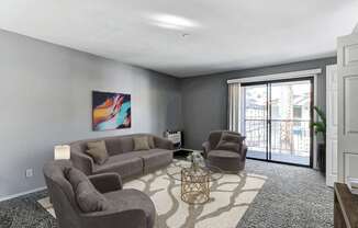 A living room with a grey couch, a brown armchair, and a painting on the wall.