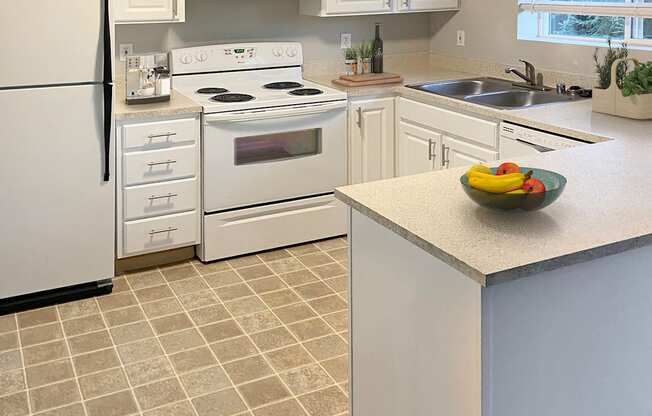 U-shaped kitchen with full-size fridge, stovetop and oven, sink with garbage disposal, dishwasher, and white cabinets.at Sitka Heights, Fife