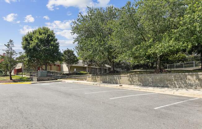 an empty parking lot with trees and a building in the background