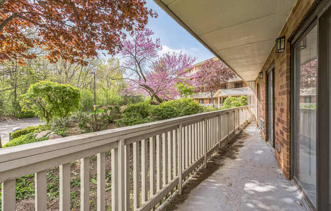 A balcony with a railing and a view of a garden and houses.