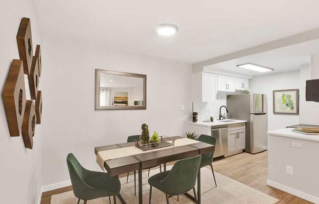 A modern dining room with a table set for two and a kitchen in the background.