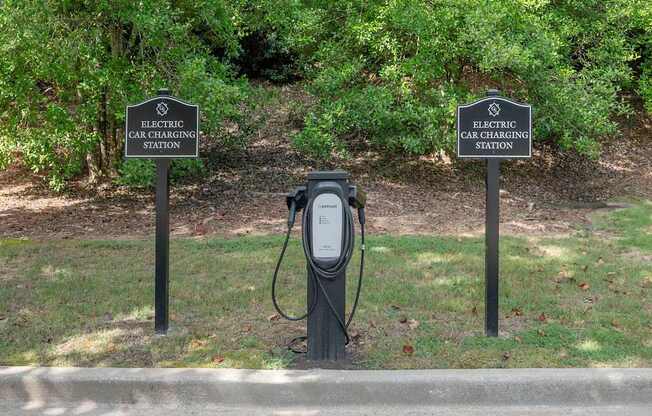 Two signs that say Electric Car Charging Station stand behind a charger.