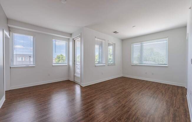 A room with wooden floors and three windows.