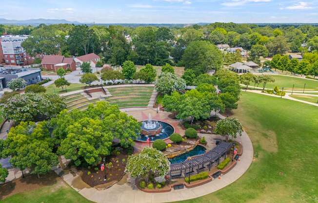 A large green park with a fountain and seating area.