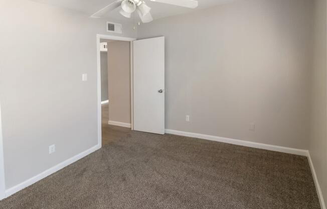 a spacious bedroom with plush carpeting and a ceiling fan with a light kit